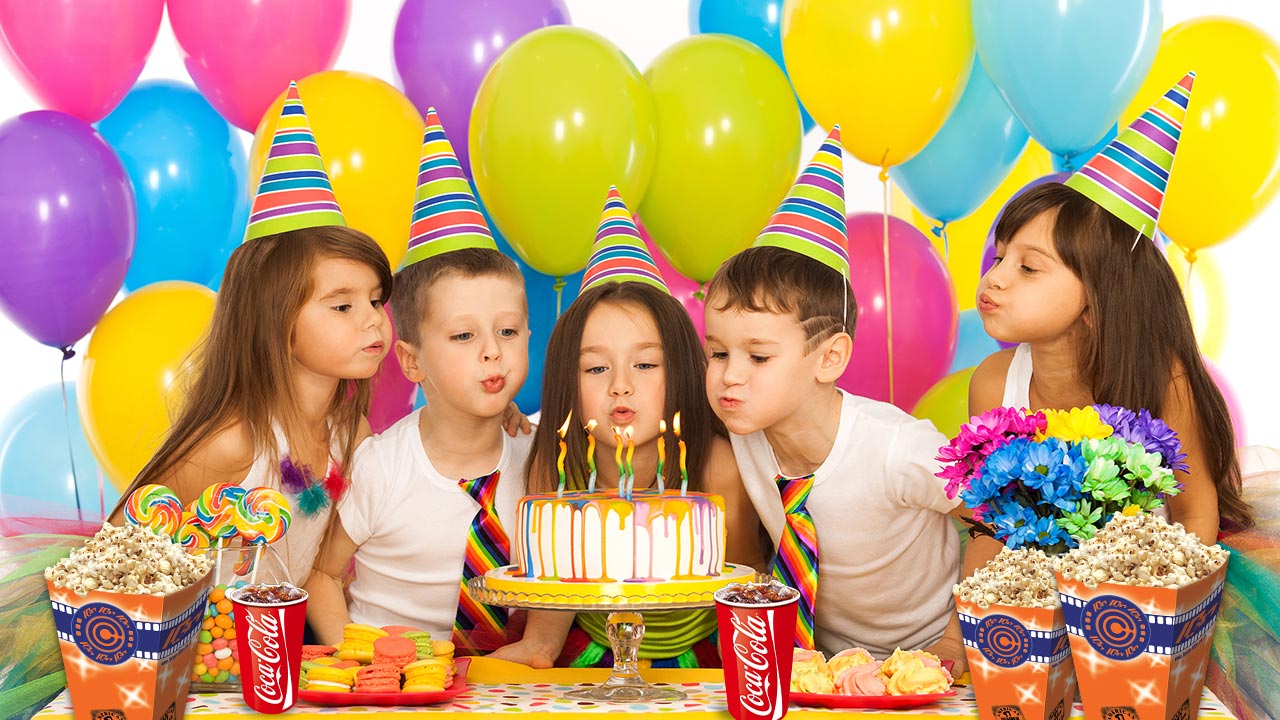 תמונת ילדים סביב שולחן יום הולדת עם ממתקים ופופקורן